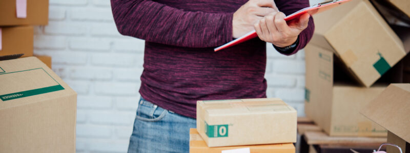 Handsome Young man working with papers among parcels at table in delivery department. online concept